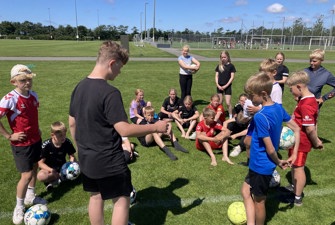 Børn bliver undervist på en fodboldbane
