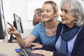 Kvinde underviser ældre kvinde i computer