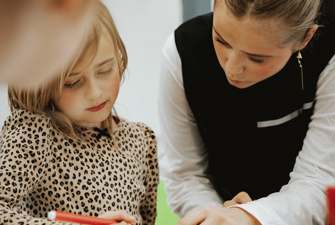 Kvindelige elev hjælper yngre skoleelev